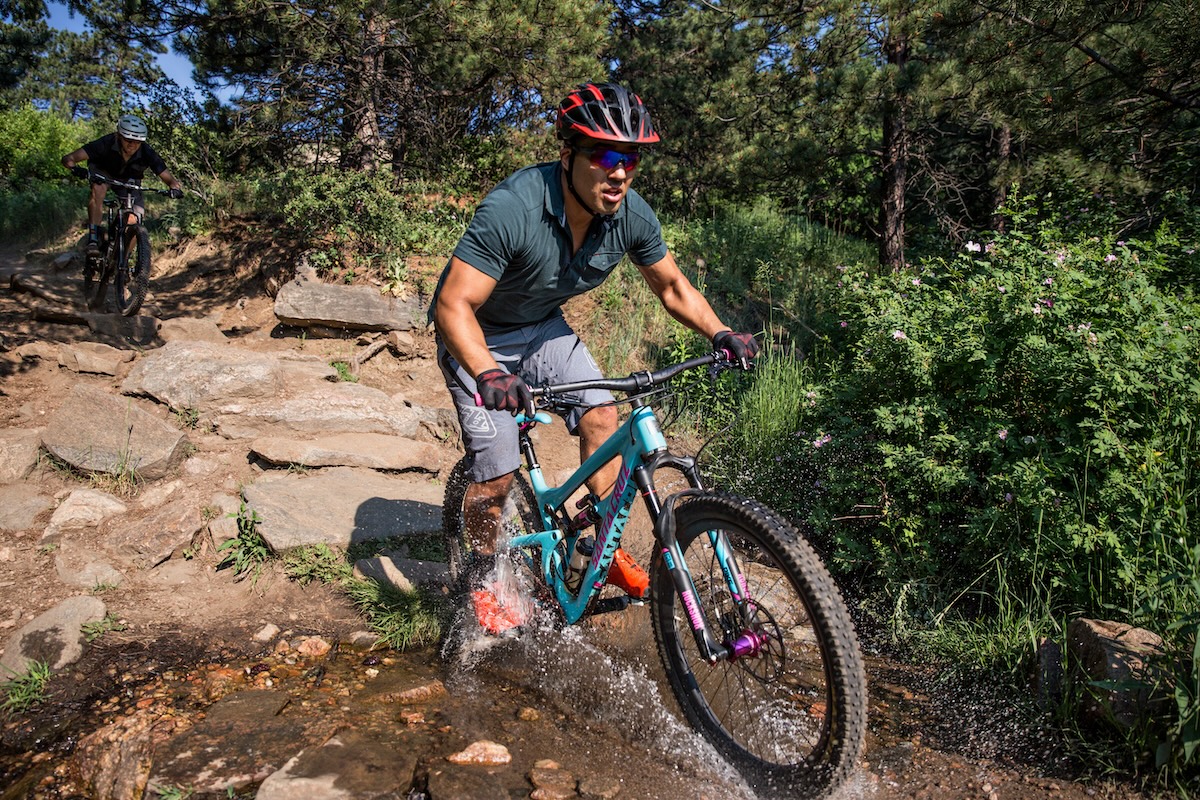 Man riding a demo mountain bike through a creek in Denver
